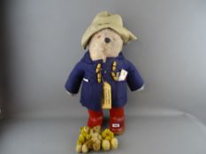 Paddington Bear stuffed toy, his duffel coat pockets stuffed with various vintage bank notes etc