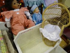 Black doll with pink check type dungarees seated on an elbow chair, a baby boy doll in blue outfit