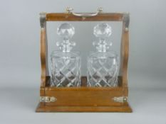 A MAHOGANY TWO BOTTLE TANTALUS with electroplate mounts and carry handle, locking with key (