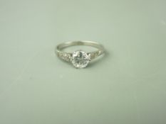 A PLATINUM DRESS RING with round cut diamond solitaire set in shoulders with tiny diamonds, 0.8