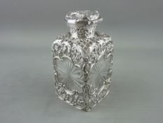 A SQUARE STARCUT GLASS COLOGNE BOTTLE having scrolled and latticed silver shoulders with silver
