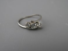 A PLATINUM CROSSOVER DRESS RING having three diamonds of visual estimate 0.2, 0.4, 0.2 carat,