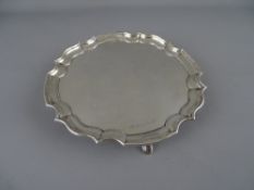 A CIRCULAR SILVER CARD TRAY WITH WAVY BORDER on four hoof feet, Sheffield 1961, 5 troy ozs, 15.5 cms