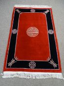 Oriental woolen red and black carpet with medalion designs and tassle ends 200 x 120cms