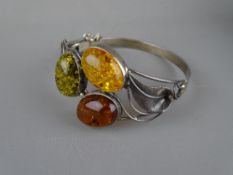 AN UNMARKED SILVER LEAF BRACELET having three large cabochon amber stones in green, light orange and
