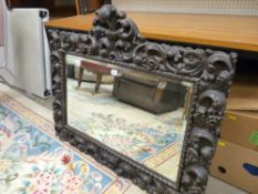 A HEAVILY CARVED OAK WALL MIRROR, 82 cms high, 100 cms wide