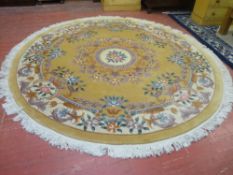 A LARGE CIRCULAR WASHED WOOLLEN CHINESE RUG, muted tones with colourful floral pattern and tasselled