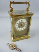 A FRENCH BRASS CASED CARRIAGE CLOCK, enamel dial with gilt centre and mask, 14.25 cms high handle