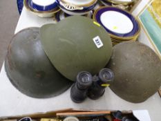 Two steel military helmets and one other and a pair of vintage field binoculars