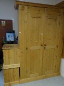 A large two-door pine wardrobe together with a pair of matching pine bedside cupboards