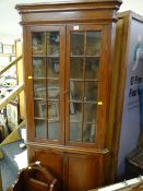 A neat stained pine standing corner cupboard, glazed upper & cupboard base on raised feet