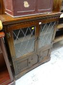 A dark oak Old Charm-style glazed top bookcase with cupboard base