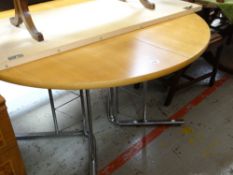 A modern lightwood circular chrome leg dining table