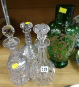 Three cut glass decanters together with a painted green glass vase