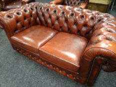 A modern red leather two-seater chesterfield sofa