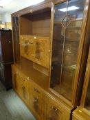 A large modern lightwood & decorated lounge unit, pull down cupboard flanked by glazed display