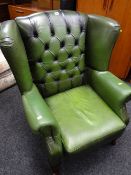 A modern green leather buttoned wingback armchair