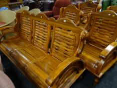 A hand crafted Malaysian teak three-seater sofa together with a similar matching armchair