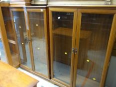 A pair of teak glazed bookcases together with a matching narrow teak bookcase
