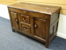 An antique oak coffer with hinged half lid & drawer with cupboard base