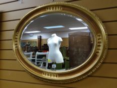 A modern oval & wooden gilt framed bevel wall mirror