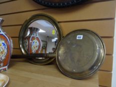 A circular brass framed wall mirror together with a brass bed warming pan