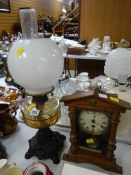 A vintage oil lamp with amber glass reservoir & metal base together with a wooden mantel clock