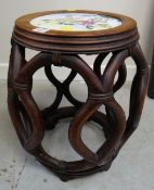 An Oriental hardwood stool with decorated ceramic seat