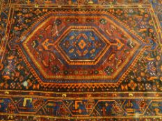 AN EASTERN WOVEN WOOLLEN CARPET, predominantly red ground with central multi-bordered motif, 205 x