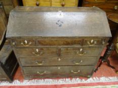 AN EARLY 19th CENTURY OAK BUREAU, the slope front revealing interior well and numerous stepped