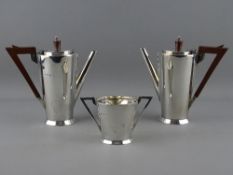 A SILVER THREE PIECE ART DECO COFFEE SET of two coffee pots with angular bakelite handles and
