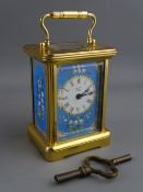 A HALCYON DAYS MINIATURE CARRIAGE CLOCK having blue enamelled side panels and mask around a circular