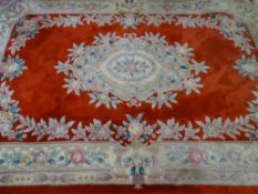 A RED GROUND CHINESE WASHED WOOLLEN CARPET with all over floral pattern and tasselled ends, 280 x