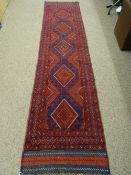 A MESHWANI CARPET RUNNER, predominantly red ground with diamond central pattern and triple