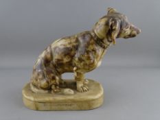A CARVED SOAPSTONE FIGURE OF A DACHSHUND seated on an oval base, the rear inscribed 'M Neumarch', 20