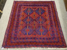 A CAZAK RUG in tonal reds and blues, multi-bordered with block diamond central pattern, 127 x 123