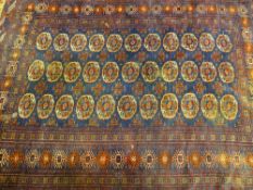 A PERSIAN STYLE RUG, predominantly blue ground in traditional style repeating patterns and tasselled