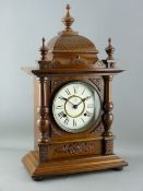 A GERMAN WALNUT CASED MANTEL CLOCK, eight day pendulum driven movement striking on a gong, 53 cms