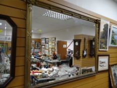 A large bevelled wall mirror in a Classical architectural gilded frame