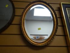 A small gilt framed oval bevelled wall mirror