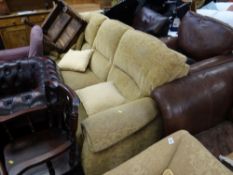 A modern three-seater sofa upholstered in an oatmeal coloured fabric