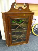 An antique single-door glazed mahogany hanging corner cabinet