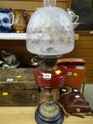 A vintage oil lamp with red glass reservoir