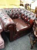 An antique red coloured chesterfield-style club armchair