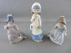 Two Nao figurines of young girls playing with puppies and one other