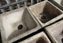 A pair of composite stone square planters on a low plinth (outside)