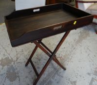 An antique butler's tray on folding stand