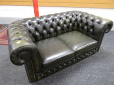 A green leather chesterfield-style two-seater sofa