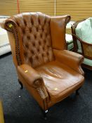 A buttoned leather studded wingback armchair (distressed)