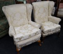 A pair of gold upholstered floral wingback armchairs
